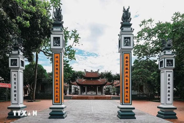 Trục thần đạo dẫn vào đình Phúc Xá, hai bên là hệ thống trụ biểu và câu đối, phía sau là mái đình cổ, nơi thờ Thái úy Việt Quốc công Lý Thường Kiệt, danh tướng Đào Kỳ, Phương Dung công chúa và các vị thành hoàng được người dân tôn kính. (Ảnh: Phạm Tuấn Anh/TTXVN)