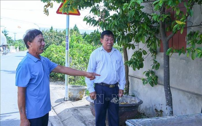 Cựu chiến binh Đỗ Đình Giao (trái) chia sẻ cùng đồng đội về diện tích đất đã hiến để mở rộng đường giao thông.