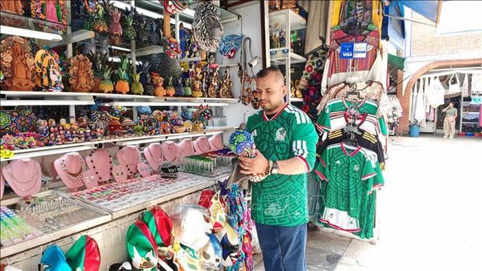 Chủ cửa hàng chỉnh trang mô hình cúp FIFA World Cup 2026 mang đậm sắc màu nghệ thuật thủ công Huichol truyền thống của Mexico.
