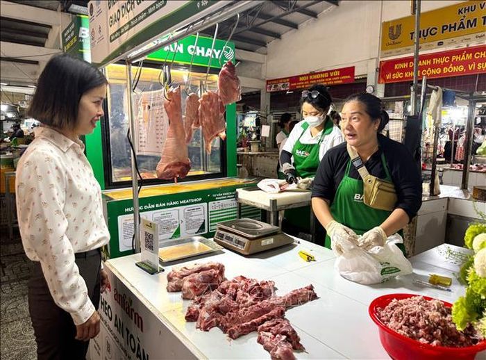 Đại diện phường Tân Mỹ trò chuyện với tiểu thương tham gia bán thịt "Tick xanh trách nhiệm" tại chợ Tân Mỹ, TP. Hồ Chí Minh. Ảnh: Hương Giang/TTXVN