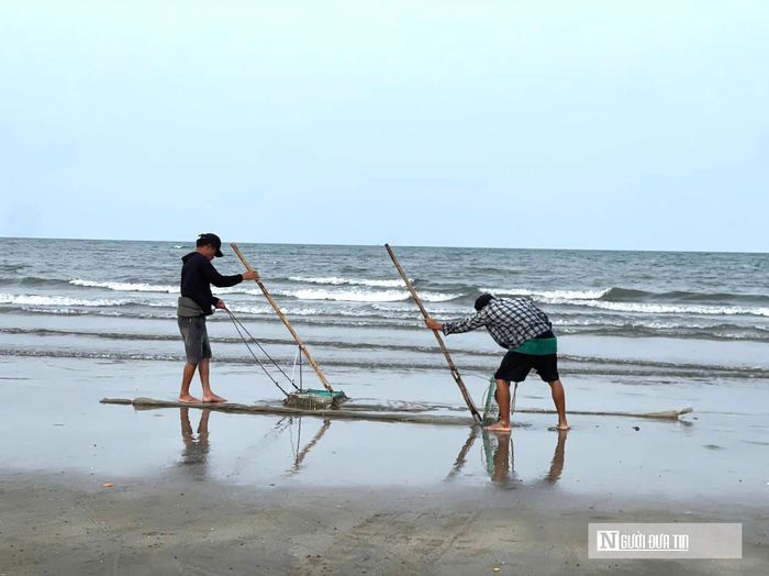 Dụng cụ cào bắt ốc cườm được ngư dân tự chế bằng chiếc khung hình chữ nhật. Đợi khi thủy triều xuống, ngư dân đi giật lùi, dùng sức kéo cào trên lớp cát dưới nước để ốc lọt vào lưới.
