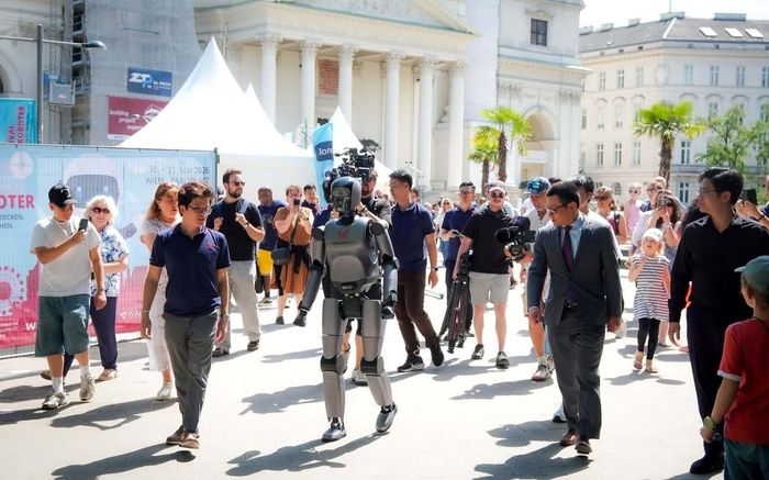 VR-H3 của VinRobotics thu hút sự chú ý với khả năng di chuyển tự nhiên tại Festival der Roboter 2026, dưới sự chứng kiến của Đại sứ Việt Nam tại Áo, ông Vũ Lê Thái Hoàng (thứ hai từ phải sang trái, hàng trên), cùng đông đảo khách tham quan quốc tế. Nguồn: VinRobotics