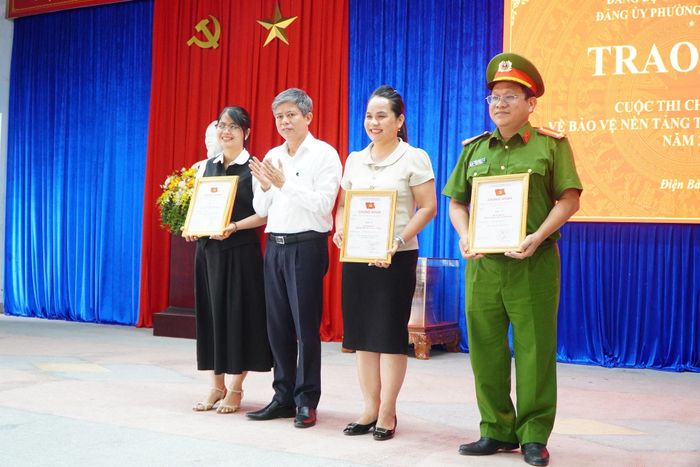 Ông Võ Văn Hùng, Bí thư Đảng ủy, Chủ tịch HĐND phường Điện Bàn Đông (thứ 2, từ trái qua) trao giải A cho các tác giả. Ảnh: TÂM ĐAN