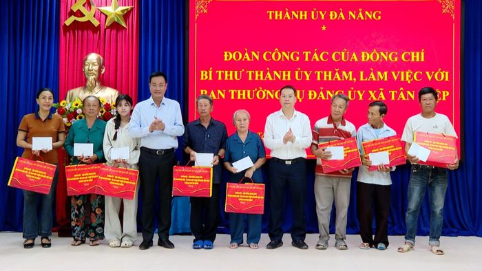 Bí thư Thành ủy Lê Ngọc Quang (thứ 4, trái sang) và Chủ tịch UBND thành phố Nguyễn Mạnh Hùng (thứ 4, phải sang) trao quà cho gia đình có công cách mạng xã Tân Hiệp. Ảnh: VĂN HÙNG - HOÀN VŨ