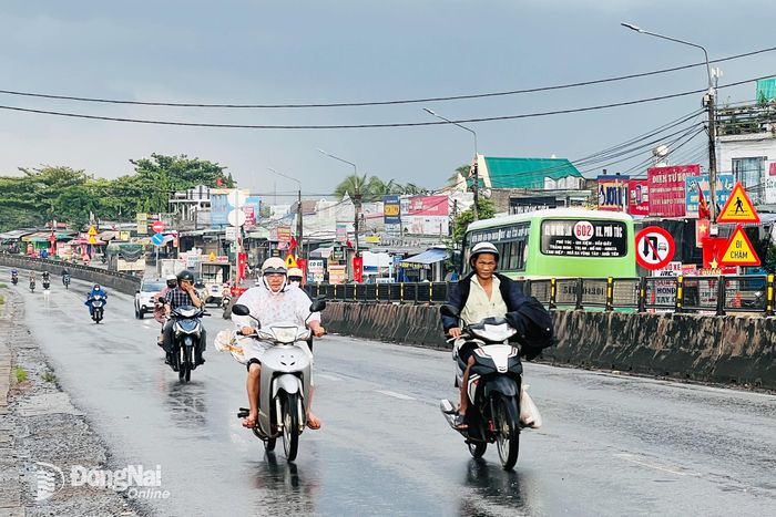 Người dân di chuyển trong trời mưa trên quốc lộ 1, đoạn qua phường Trảng Bom, thành phố Đồng Nai.
