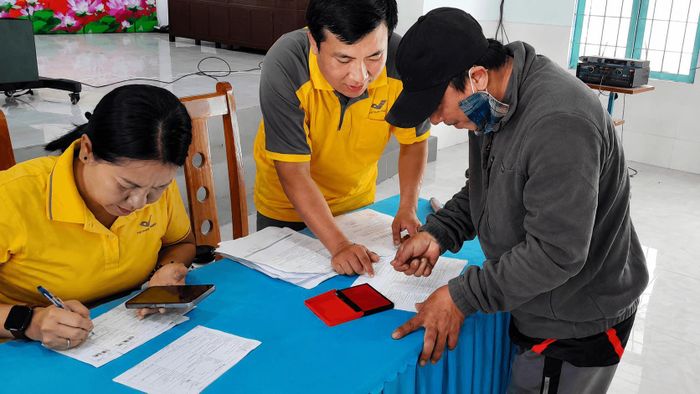 Nhân viên Bưu điện hướng dẫn người dân hoàn thiện hồ sơ, đối chiếu thông tin trước khi nhận tiền hỗ trợ