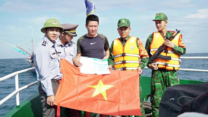 Lực lượng kiểm ngư và cán bộ Đồn Biên phòng Cồn Cỏ tặng cờ Tổ quốc, tuyên truyền các quy định chống khai thác IUU cho ngư dân Lê Văn Ngọc, thuyền trưởng tàu cá QNg 11144TS đang hoạt động trên vùng biển đảo Cồn Cỏ - Ảnh: L.A
