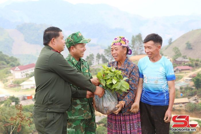 Nhân dân bản Móng Nặm (Lào) phấn khởi nhận cây giống từ cán bộ Đồn Biên phòng Chiềng Tương (Việt Nam).