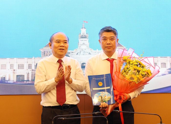 Phó Chủ tịch UBND TPHCM Trần Văn Bảy trao quyết định và tặng hoa chúc mừng ông Lê Hoài Phong
