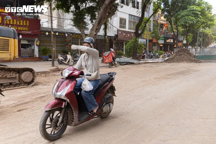 Thời tiết nắng nóng cùng lượng bụi phát sinh từ công trường khiến người dân phải che kín mặt khi đi qua khu vực.