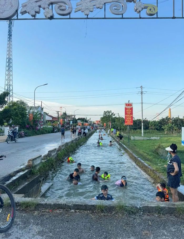 Hàng chục người dân, từ trẻ nhỏ đến người lớn, tập trung tắm mát tại một con mương ở vùng quê Thanh Hóa.