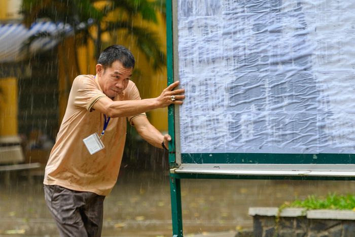 Cơn mưa bất chợt kèm những đợt gió mạnh quật qua sân trường đã thổi bật chiếc dù lớn đặt giữa khuôn viên điểm thi, khiến bảng niêm yết thông tin và số báo danh của thí sinh bị mưa hắt ướt. Phát hiện sự việc, một cán bộ điểm thi lập tức di chuyển bảng vào khu vực có mái che. Tuy nhiên, do cơn mưa kéo đến quá nhanh, nhiều phần thông tin trên bảng vẫn bị thấm nước.