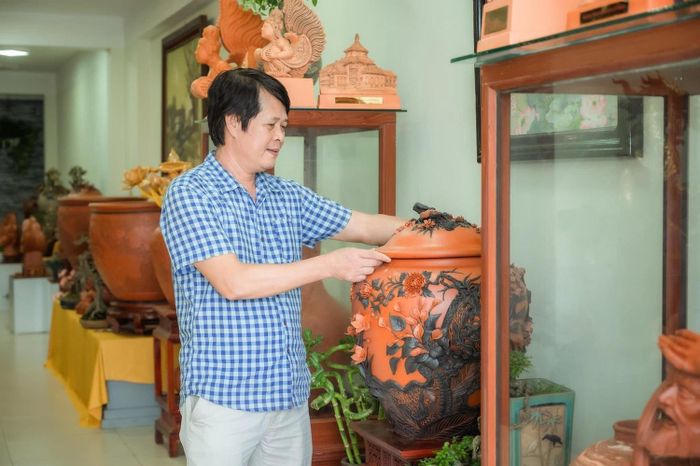 Nghệ nhân Đỗ Tùng Mậu bên cạnh những sản phẩm Gốm son đỏ. Ảnh: NVCC