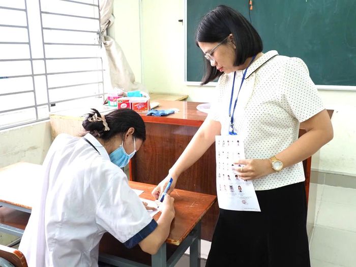  Cán bộ coi thi hướng dẫn thí sinh kiểm tra thông tin trên giấy báo dự thi. Ảnh: THU TÂM 