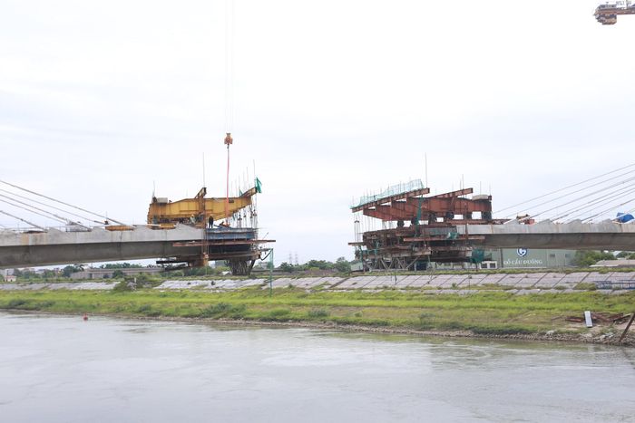 Nhà thầu hiện đang đẩy nhanh tiến độ thi công các đốt dầm theo phương pháp đúc hẫng cân bằng, từng bước vươn ra giữa sông để chuẩn bị hợp long nhịp chính, đồng thời tăng tốc thi công các trụ dẫn và đường dẫn hai đầu cầu.