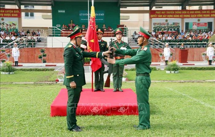 Trung tá Phạm Đình Cường (trái), Trung đoàn trưởng Trung đoàn Gia Định thực hiện nghi thức trao vũ khí cho chiến sĩ mới.