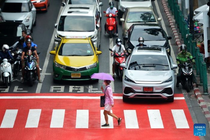Người đi bộ băng qua đường với chiếc ô che nắng ở Bangkok, Thái Lan. Ảnh: Tân Hoa xã