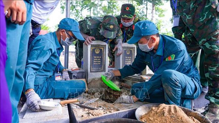 Lực lượng chức năng tiến hành khai quật, lấy mẫu hài cốt liệt sĩ chưa xác định thông tin tại Nghĩa trang liệt sỹ Dương Minh Châu để phục vụ công tác giám định ADN. Ảnh: Minh Phú/TTXVN