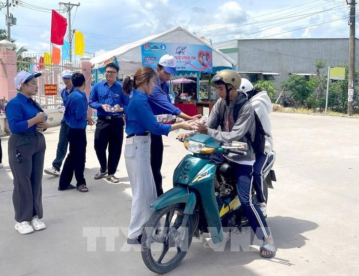 Đội hình tiếp sức mùa thi hỗ trợ thí sinh nước uống trước khi vào làm thủ tục dự thi. Ảnh: Lê Thúy Hằng – TTXVN