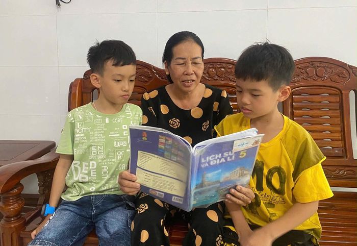 2 con trai của chị Nguyễn Thị Tâm đọc sách cùng bà nội. Ảnh: CẨM TÚ