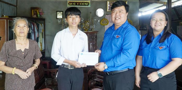 Phó Bí thư Tỉnh đoàn, Chủ tịch Hội Sinh viên tỉnh An Giang Dư Phạm Hữu Khuyến (thứ hai, từ phải qua) trao hỗ trợ cho thí sinh Trương Đặng Thanh Danh, học sinh lớp 12A9, Trường THPT Châu Phú, xã Mỹ Đức.