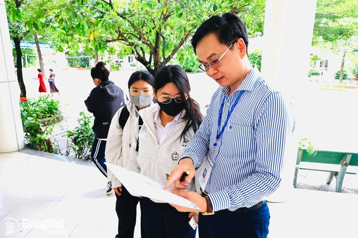 Giám thị coi thi tại điểm thi Trường THPT chuyên Lương Thế Vinh hướng dẫn sơ đồ phòng thi cho thí sinh. Ảnh: CN
