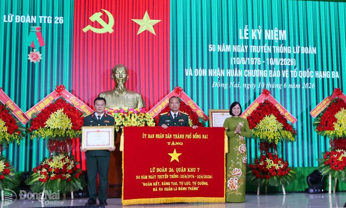 Thành ủy viên, Phó Chủ tịch UBND thành phố Nguyễn Thị Hoàng trao bức trướng của UBND thành phố chúc mừng Lữ đoàn 26. Ảnh: Nguyệt Hà