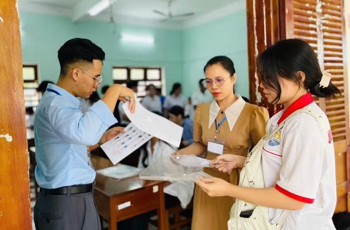 Cán bộ coi thi hướng dẫn thí sinh làm thủ tục dự thi tại điểm thi Trường Quốc học Quy Nhơn. Ảnh: Trần Dung