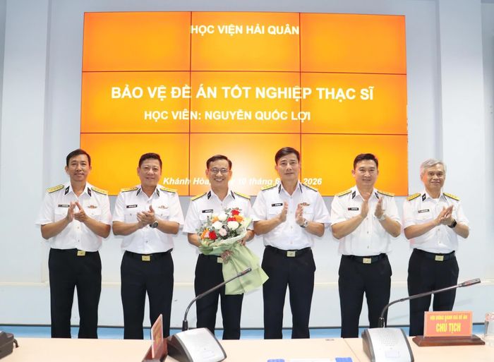 Hội đồng tặng hoa chúc mừng học viên bảo vệ đề án.