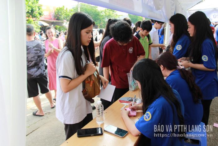 Tình nguyện viên tại điểm thi Trường THPT chuyên Chu Văn An hỗ trợ thí sinh giữ đồ cá nhân tại kỳ thi năm 2025