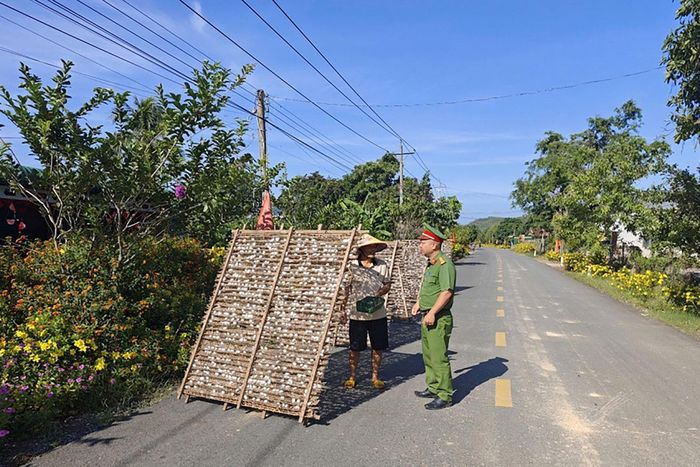 Công an xã Đạ Tẻh 2 tuyên truyền, nhắc nhở người dân không phơi nông sản trên lòng, lề đường (Ảnh Lê Tiến)