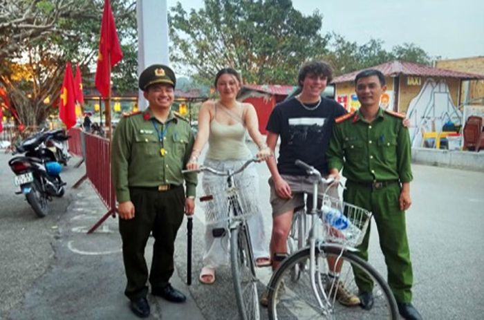 Thượng úy Hoàng Hữu Trí (ngoài cùng bên trái) giúp khách du lịch người nước ngoài tìm lại tài sản để quên trong quá trình tham quan.