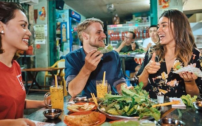 Khách du lịch quốc tế hào hứng trải nghiệm ẩm thực đường phố tại Thành phố Hồ Chí Minh, Việt Nam. Ảnh: ginkgovoyage