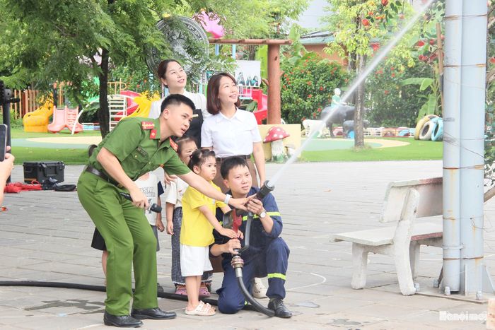 Các em học sinh trải nghiệm phun nước chữa cháy. Ảnh: PV