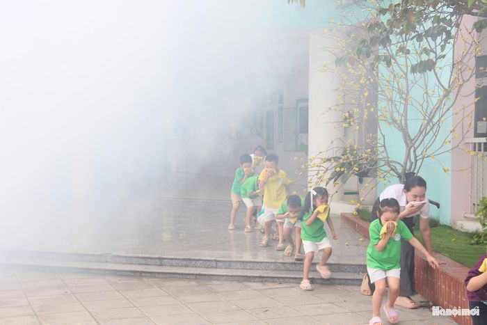 Các em học sinh trường mầm non thực hành kỹ năng di chuyển trong môi trường có khói. Ảnh: PV