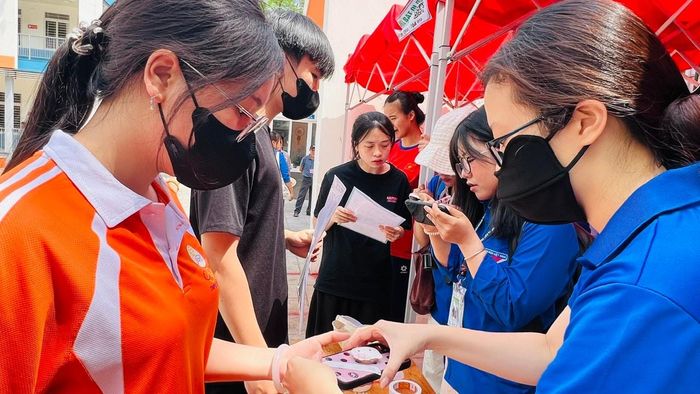 Tình nguyện viên hỗ trợ cất giữ đồ dùng không được phép mang vào phòng thi. Ảnh: Lê Hà