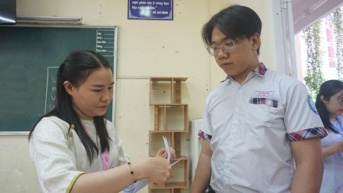  Giám thị kiểm tra giấy tờ của thí sinh. Ảnh: THUẬN VĂN 