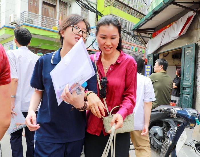 Phụ huynh chia sẻ cảm xúc với thí sinh sau khi hoàn thành môn thi đầu kỳ thi tốt nghiệp THPT năm 2026 tại điểm Trường THCS Ngô Quyền (phường Bạch Mai). Ảnh: Khánh Hòa - TTXVN
