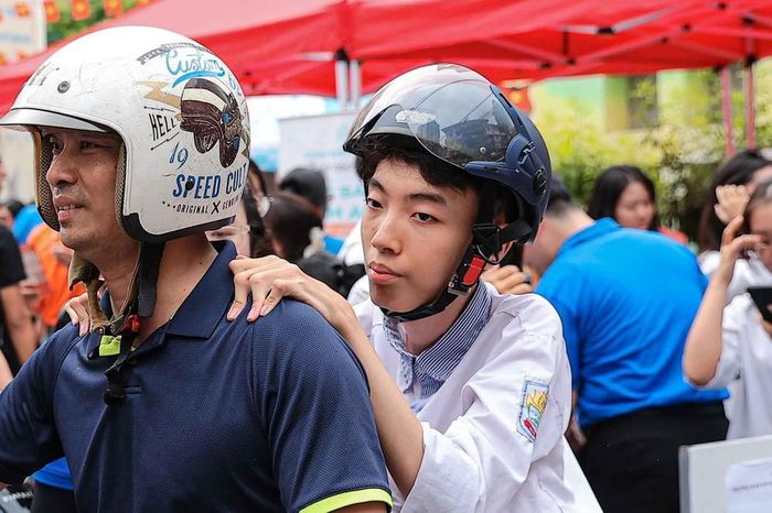 Rời điểm thi, Sơn đặt tay lên vai bố - một điểm tựa rất gần, rất quen, nơi em gửi trọn sự tin tưởng vào người đã làm “đôi chân” đồng hành cùng mình suốt 18 năm qua. Ảnh: Phạm Tuấn Anh - TTXVN
