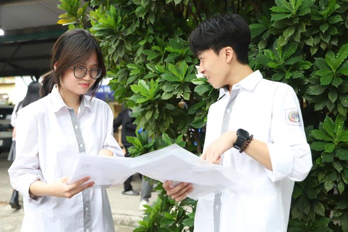 Hai thí sinh tại điểm thi Trường THPT Yên Hòa (Hà Nội) trao đổi thông tin và động viên nhau trước giờ bước vào kỳ thi quan trọng - Ảnh: VGP/Văn Hiền