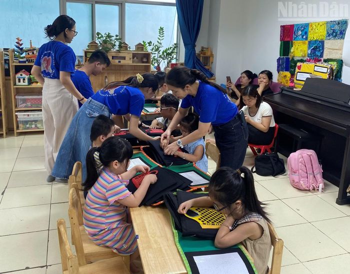 Các cô giáo hướng dẫn học sinh sờ chạm vào sách xúc giác. (Ảnh: Hà Thương)