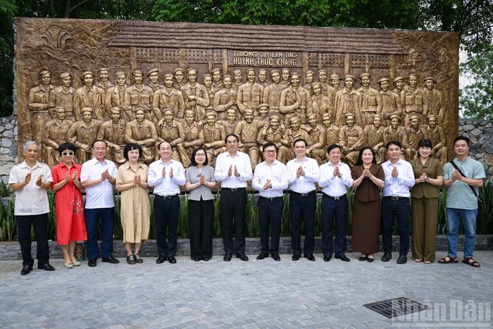Các đồng chí lãnh đạo và các đại biểu chụp ảnh lưu niệm trước tấm phù điêu chân dung 48 thành viên Ban Giám hiệu, giảng viên và học viên của Trường dạy làm báo Huỳnh Thúc Kháng.