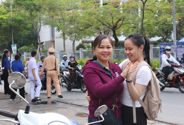 Một phụ huynh ôm con động viên tại điểm trường THPT Phan Châu Trinh. Ảnh: XUÂN QUỲNH