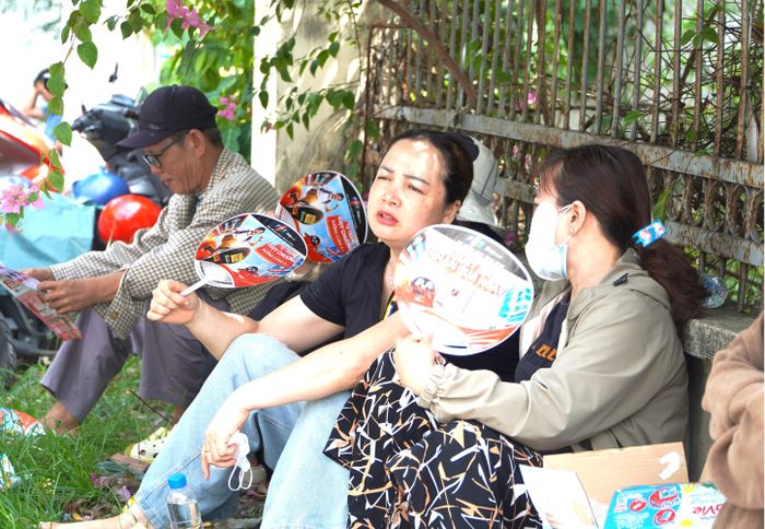 Phụ huynh chờ đón con em trong thời tiết nắng nóng. Ảnh: PHÚ NGÂN