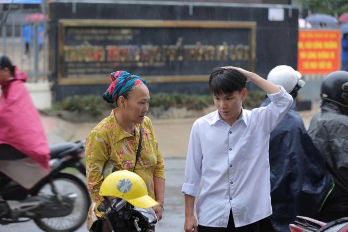 Người mẹ dân tộc Mông đầu đội khăn, dặn dò con trai trước cổng điểm thi Trường THPT Kỳ Sơn, xã Mường Xén, tỉnh Nghệ An. Ảnh: Thanh Hải
