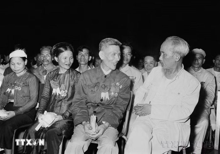 Chủ tịch Hồ Chí Minh nói chuyện thân mật với Anh hùng Lao động Nguyễn Phúc Đồng (ngành Quân giới) và nữ Anh hùng Nguyễn Thị Năm (dệt Nam Định) trong buổi họp mặt các đại biểu dự Đại hội liên hoan Anh hùng, Chiến sỹ thi đua Công-Nông-Binh toàn quốc lần thứ II (Hà Nội, 7/7/1958). (Ảnh: TTXVN)