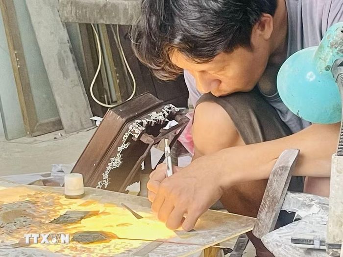 Người thợ ngày đêm cần mẫn tạo ra các sản phẩm khảm trai sơn mài Chuyên Mỹ. (Ảnh: Tuyết Mai/TTXVN)