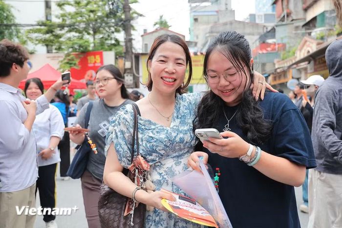 Phụ huynh và sỹ tử hòa chung một nụ cười, bước đầu cảm thấy yên tâm, sẵn sàng để bước vào môn thi bắt buộc thứ hai vào chiều nay - môn Toán. (Ảnh: Hoài Nam/Vietnam+)