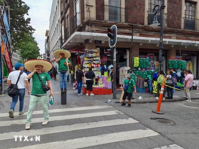 Người bán hàng chào bán mẫu áo đấu đội tuyển Mexico để thu hút khách mua. (Ảnh: Phương Lan/TTXVN)