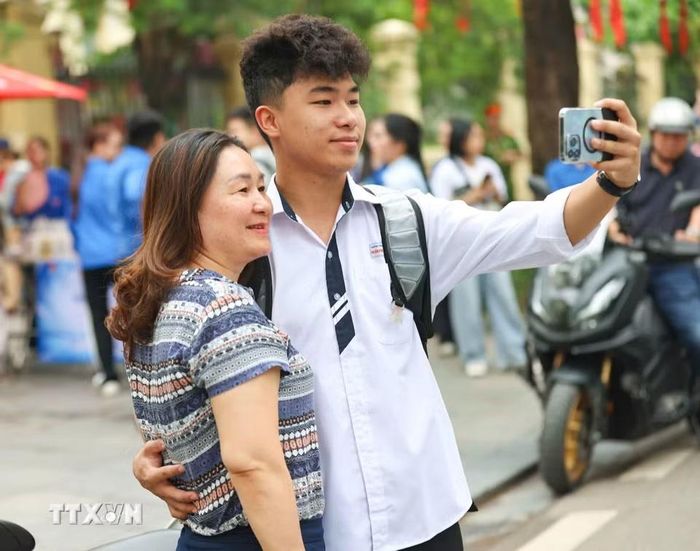 Rạng rỡ bên con trước khi con vào thi môn Toán. (Ảnh: Thanh Tùng/TTXVN)